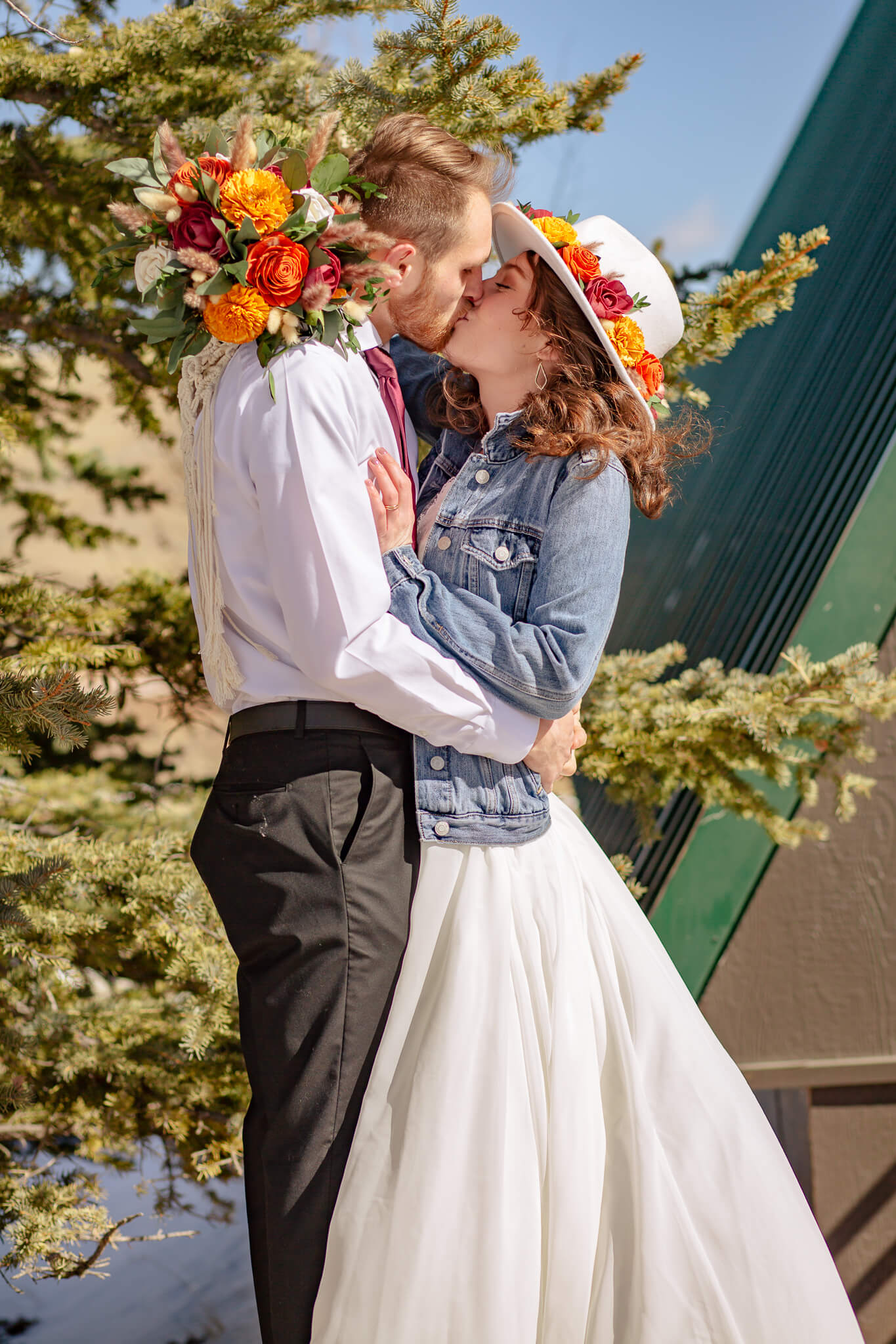 Bride and groom kissing outside cozy cabin.