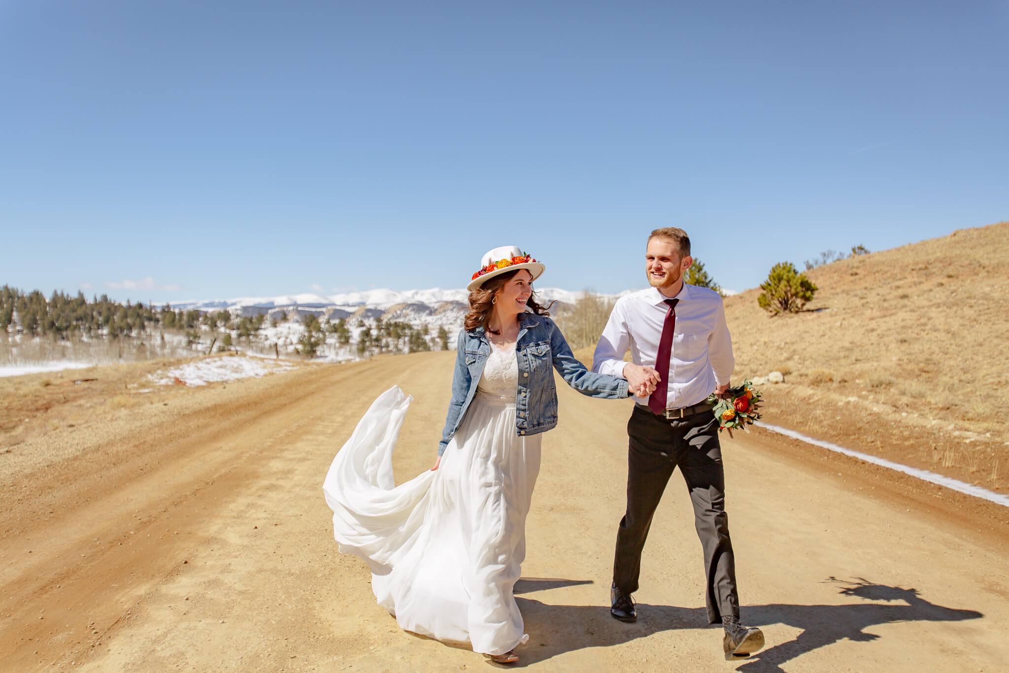 Couple holding hands and laughing on a dirt road.