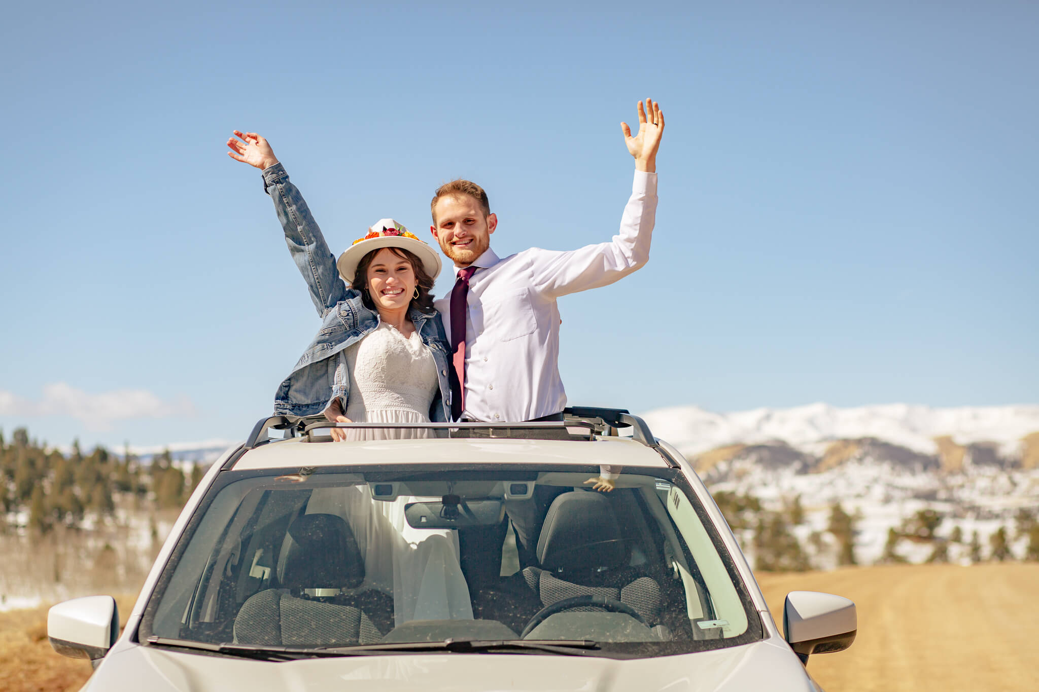 Couple waving on top of the car.