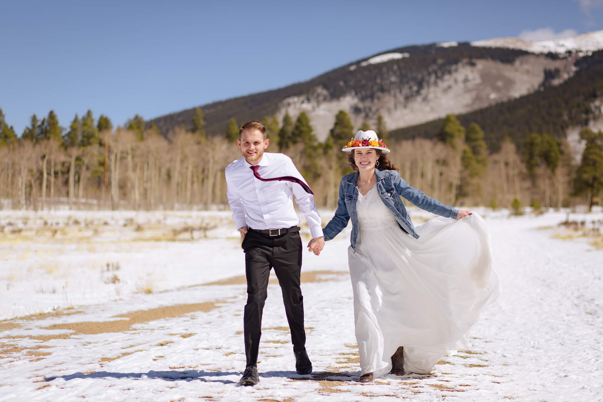 Bride and groom holding hands and posing in front of the mountains.