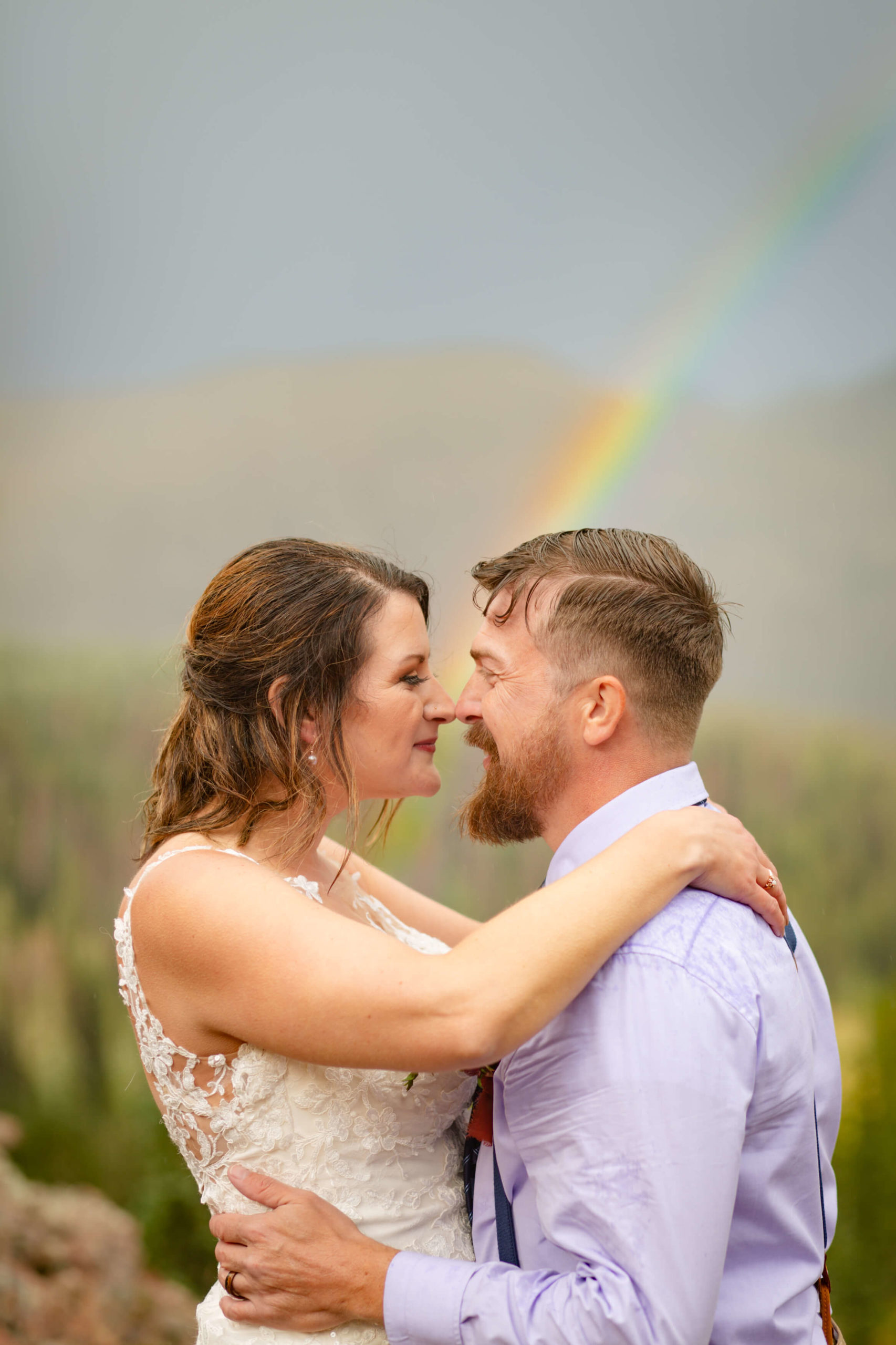 close- up of bride and groom kissing in front of rainbow