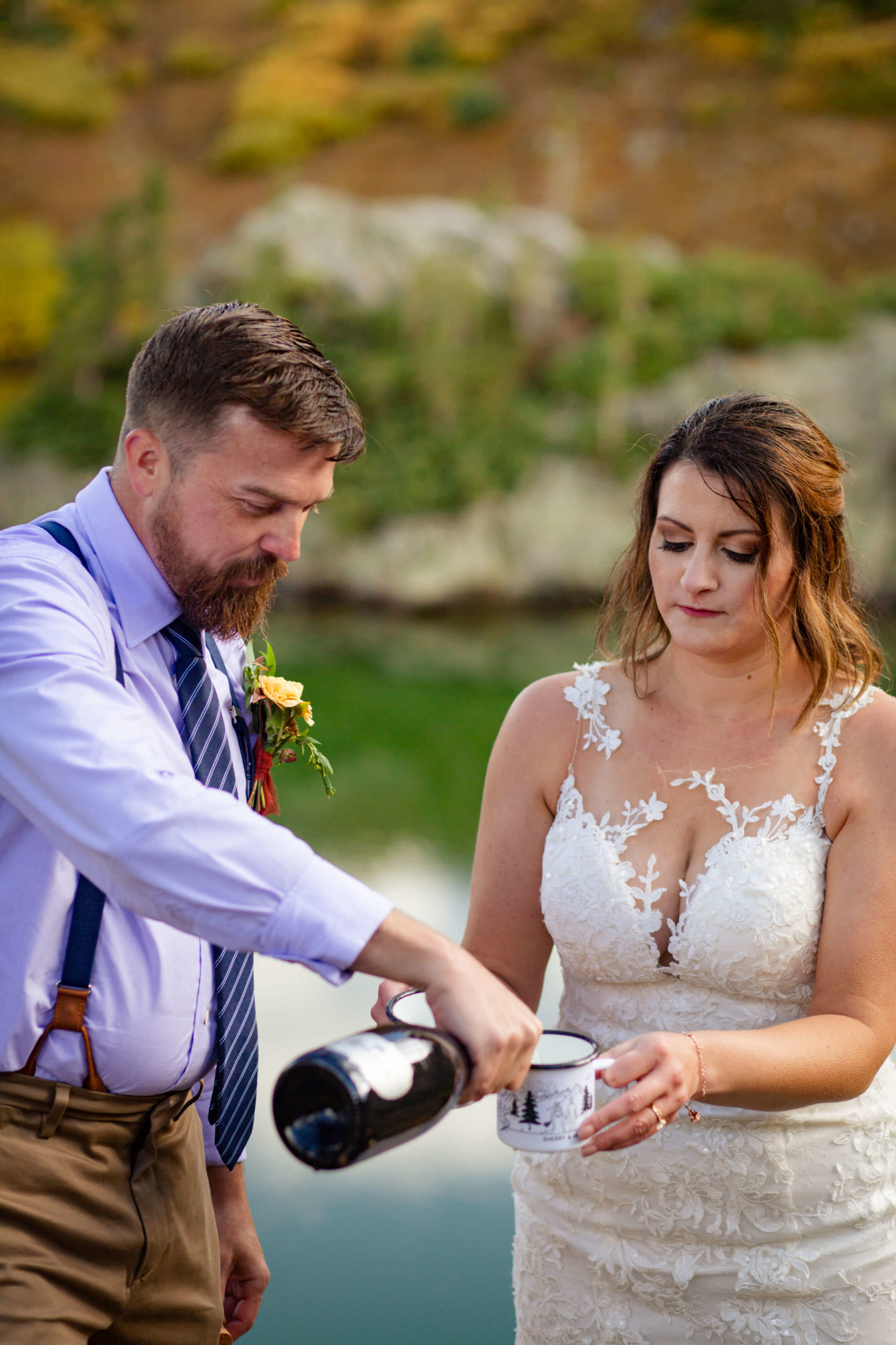 groom pouring champagne for bride in mugs