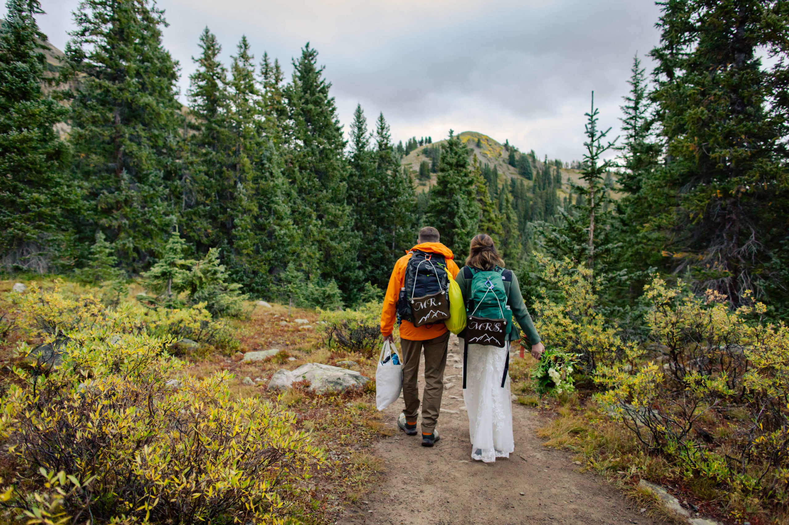 couple hiking with their gear and mr. and mrs. signs