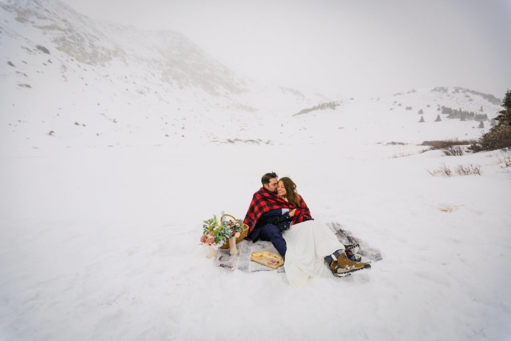 The couple holding each other while enjoying their winter picnic.