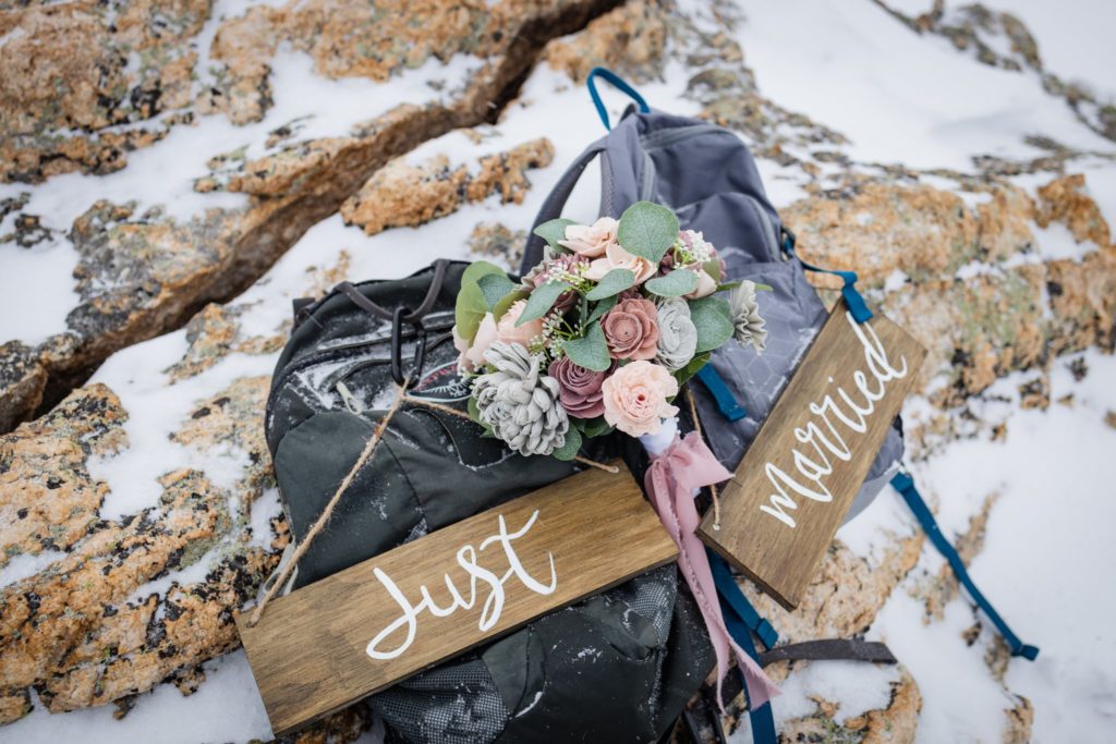 wedding details of couple's backpacks and 'just married' signs