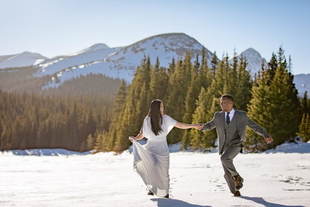 Bride and groom holding hands and running in Rocky Mountain National Park.
