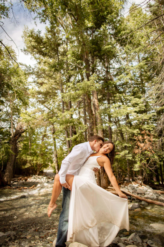 Groom holding bride as she flips her dress in Zapata Falls, Colorado.