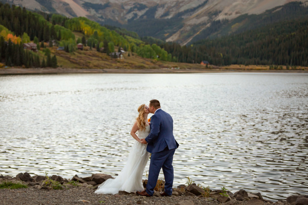 couple kissing while holding hands in front of the lake
