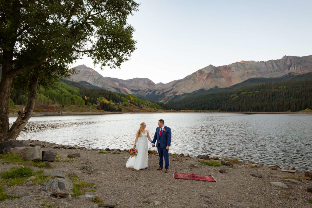 bride and groom holding hands while looking at each other in front of the telluride mountain range