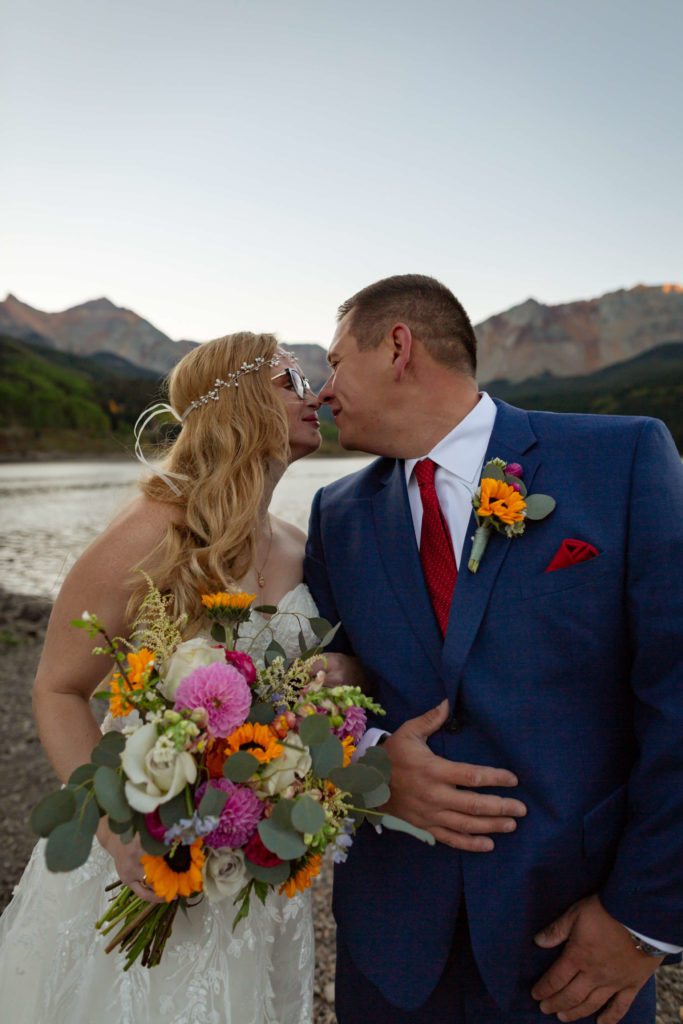 couple leaning in for a kiss in front of the telluride mountain range
