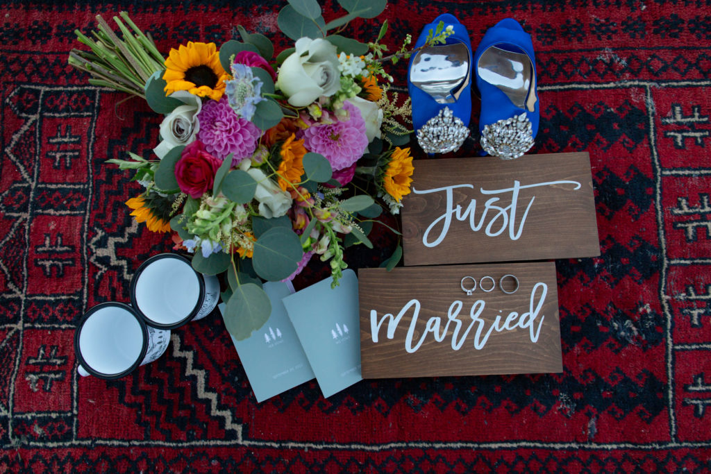 bride and groom wedding details: shoes, mugs, bouquet, vow books, rings, and 'just married' signs