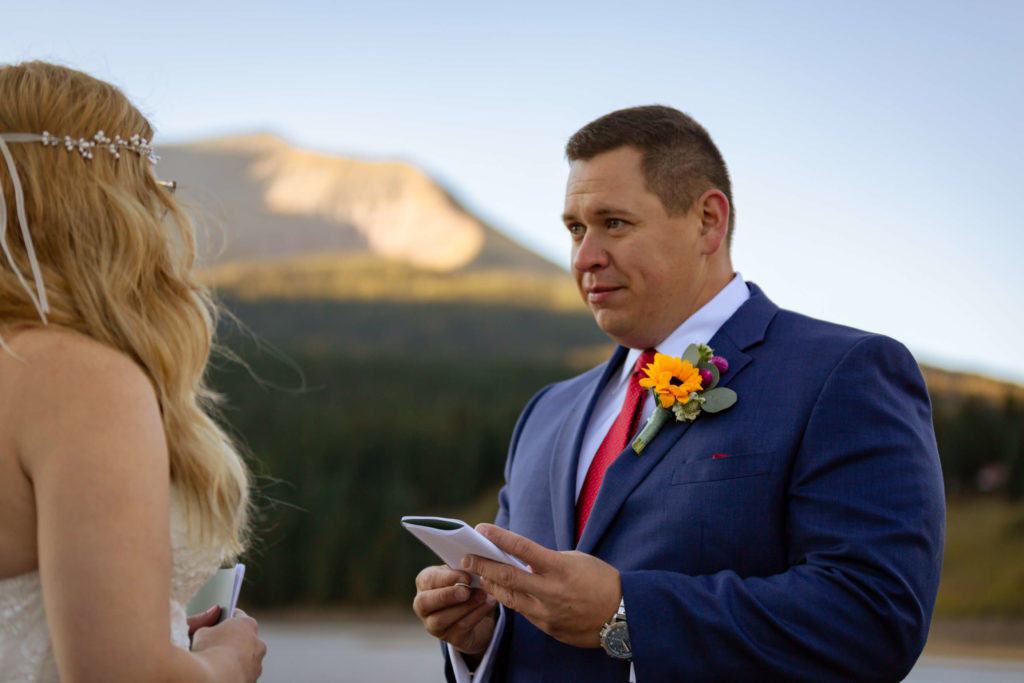 Groom looking at bride while he reads his vows to his bride to be