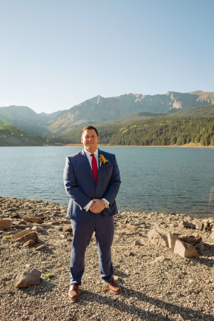 image of the groom posing in front of the lake