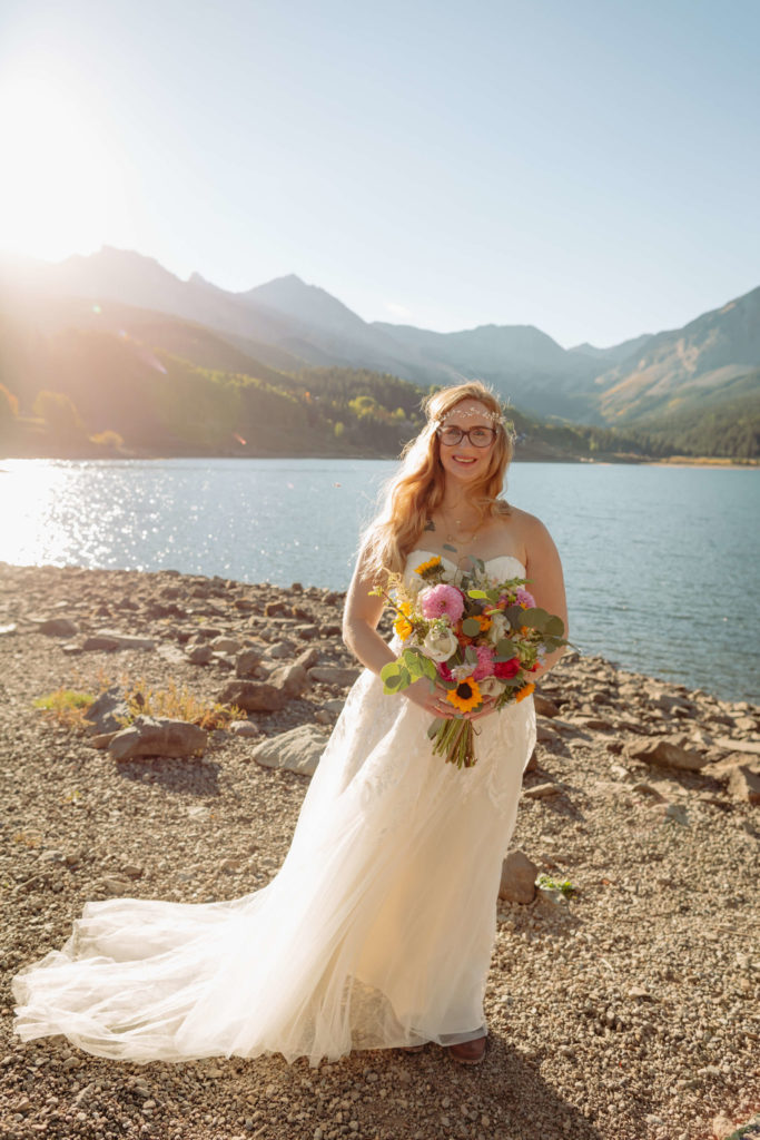 portrait of the bride posing in front of the lake while holding her bouquet