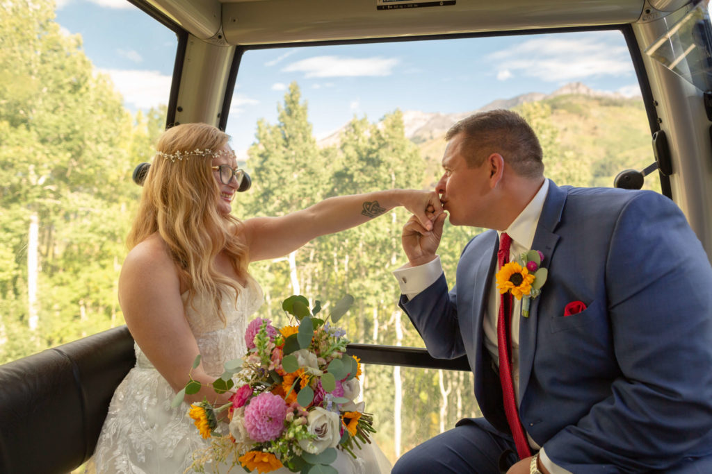groom kissing the hand of his bride while on the gondola
