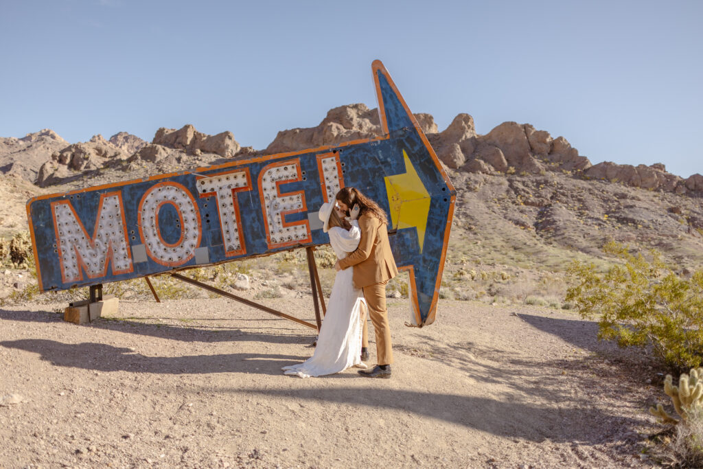 Bride and groom kiss by an old motel sign at Nelson's Ghost Town.