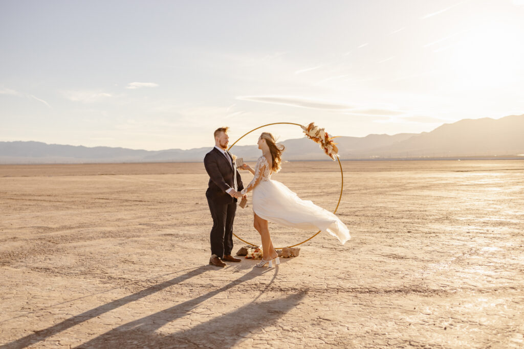Bride and groom holding hands while reading their vows to each other during their elopement at the dry lake bed in Las Vegas.