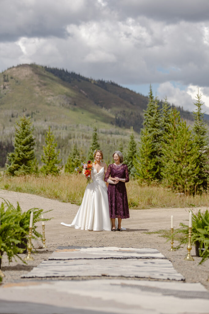 The bride and her Mom walk down the aisle with mountains as their backdrop