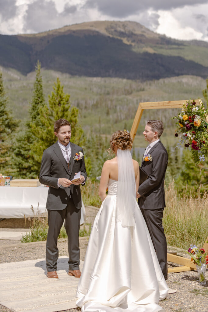 The bride and groom stand at their elopement ceremony spot, a campground in steamboat springs, surrounded by friends, family and nature