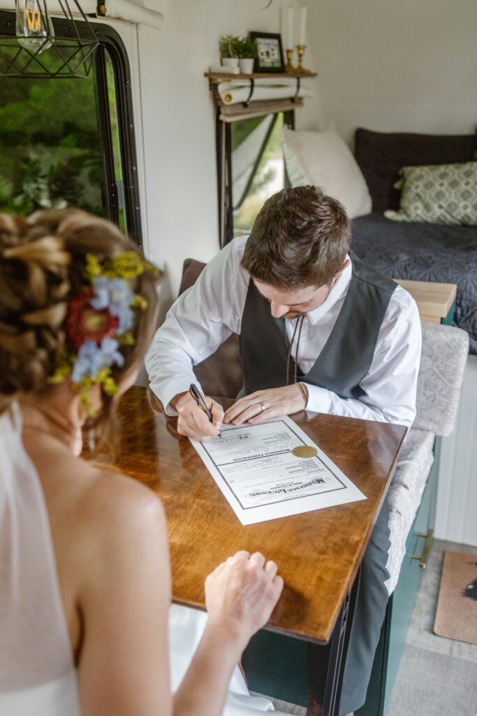 bride and groom sign their marriage license in their trailer after their elopement in steamboat springs