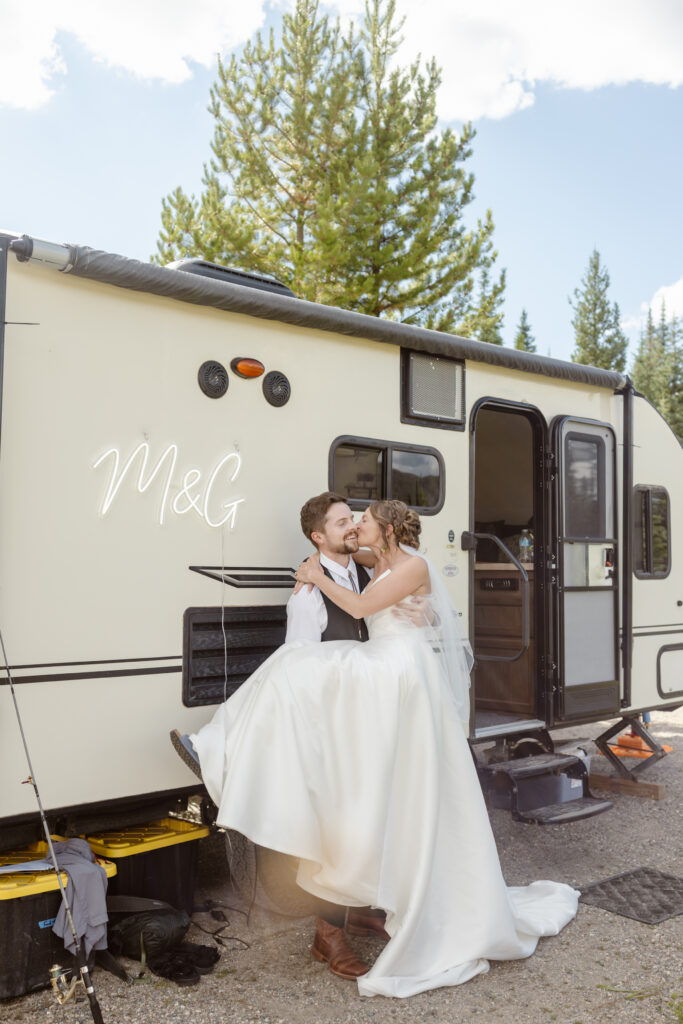 Groom picks up bride in front of their trailer at their elopement in steamboat springs