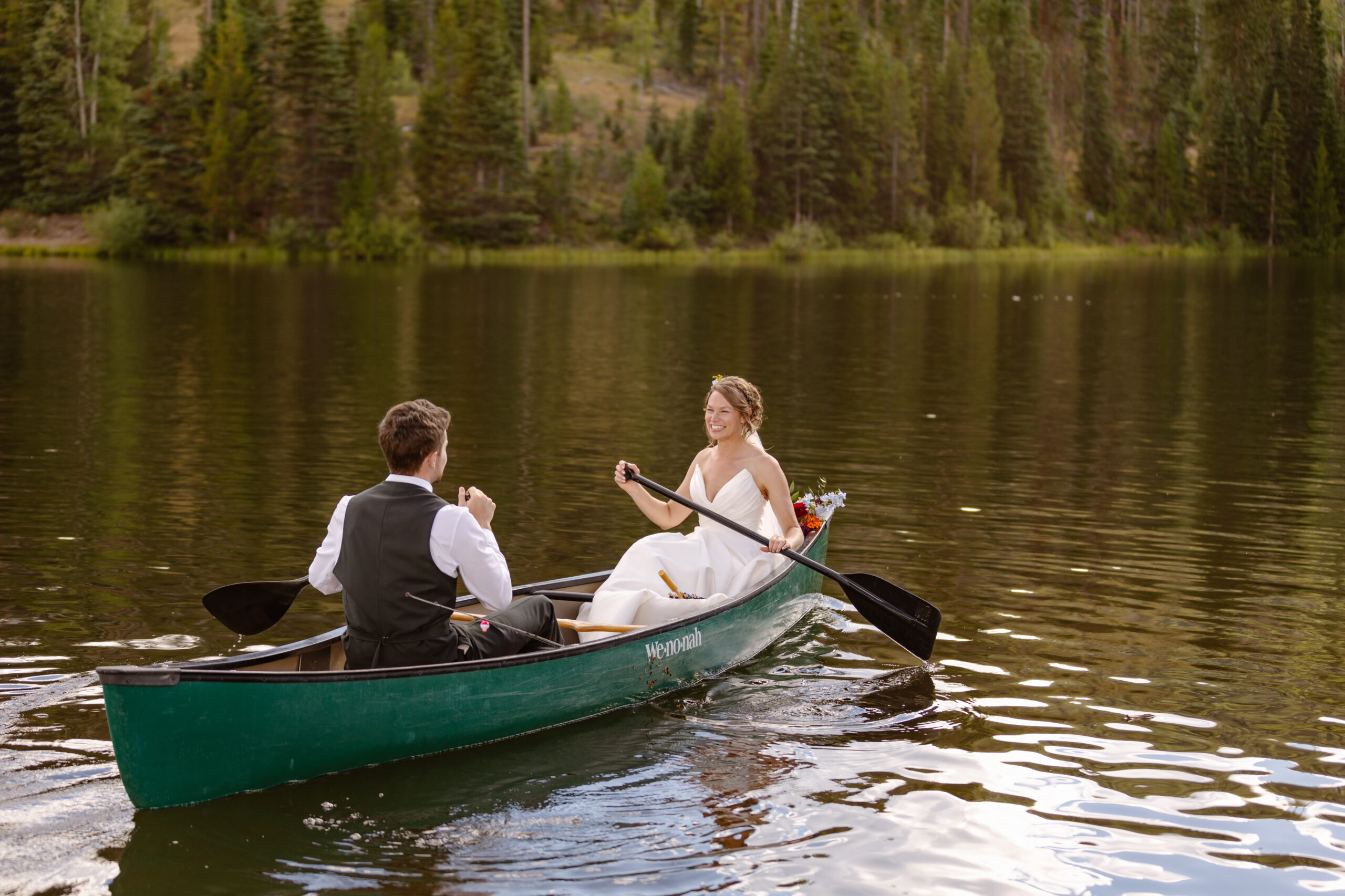 Bride and groom paddle in a canoe along Pearl Lake after their elopement