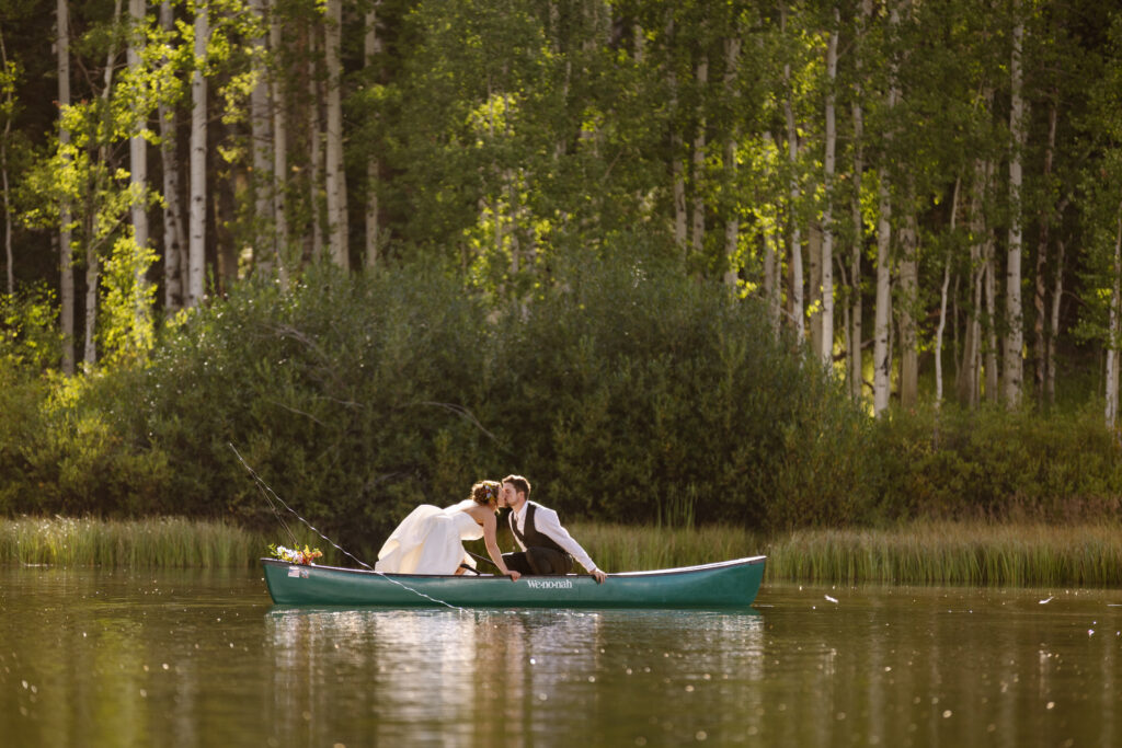 Bride and groom come together for a careful kiss while on a canoe after their elopement in steamboat springs