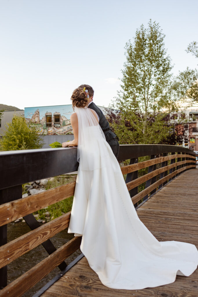 bride and groom look out over a bridge in steamboat springs